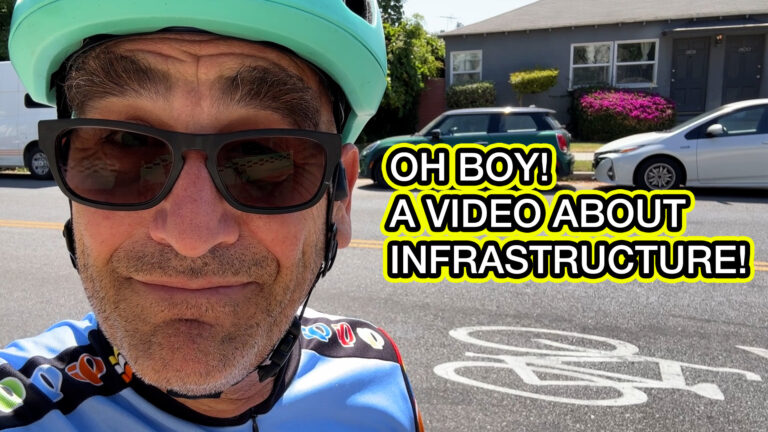 My head, looking at the camera and smiling. I'm outside, and a sharrow is visible on the street. Text on the image read: "OH BOY! A VIDEO ABOUT INFRASTRUCTURE!"