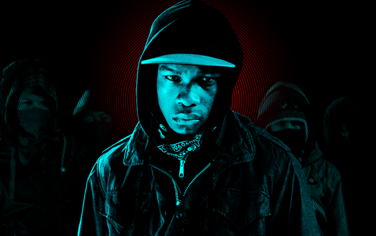 John Boyega as Moses in Attack the Block. Most of the image is black and cyan, but there is a slight red glow around his head. Other members of the cast are obscured in the background.