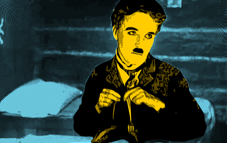 Stylized colorization of Charlie Chaplin as The Little Tramp in The Gold Rush. Chaplin is yellow and black. The top half of his body is visible, and in each hand he is holding a fork with a roll stuck in the end, giving the appearance of a huge-headed man with skinny legs and large feet. The background is cyan and black and shows the wall of a cabin, and a cot with a pillow.